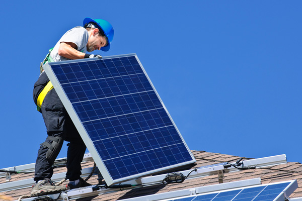 A photo of a worker installing solar panels on a roof, a common example of workers compensation insurance claims