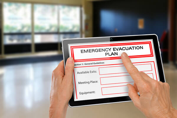 Person holding a tablet with an emergency evacuation plan in preparation for fire prevention week in Massachusetts