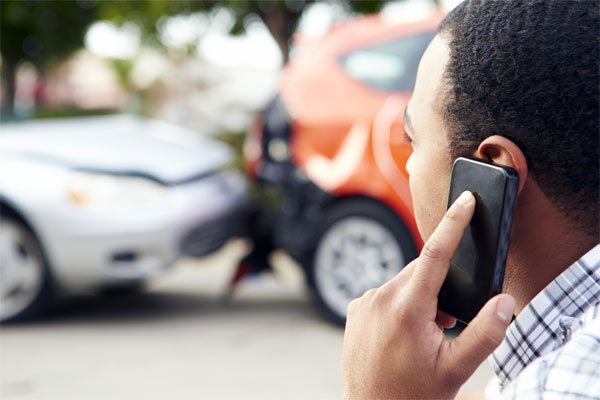 A photo of a man on the phone at the scene of a car accident